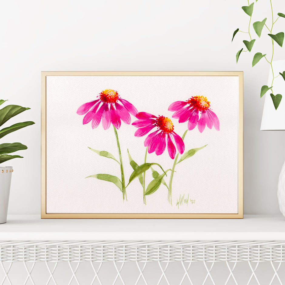 Framed artwork of pink flowers on a white wall with plants around