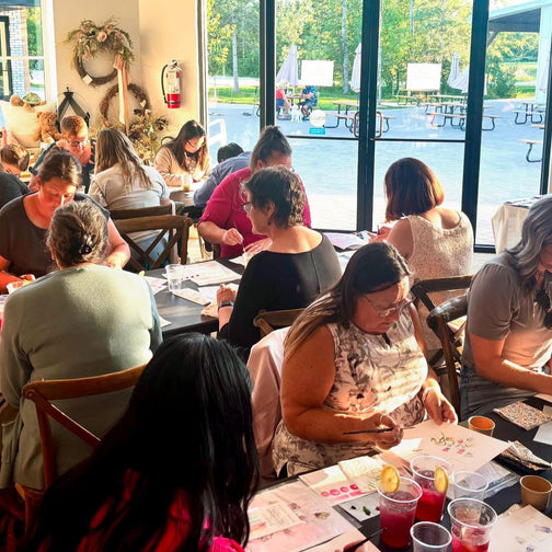 People sitting at tables in a bright room with large windows