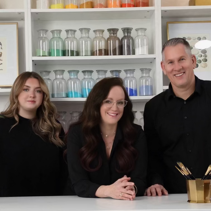 Three people standing behind a counter with decorative items on shelves in the background