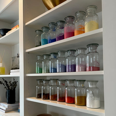 Open cabinet with glass jars and decorative items on a wooden floor.