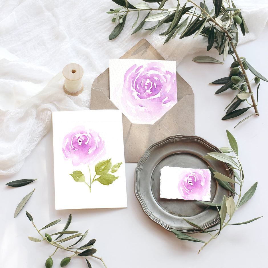 Decorative setting with floral cards and olive branches on a white surface