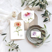 Floral cards on a table with greenery and a candle