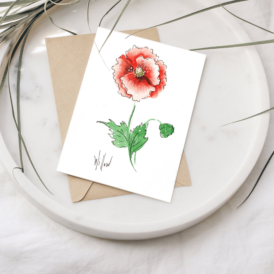Greeting card with a red flower illustration on a white plate with a brown envelope.