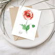 Greeting card with a red flower illustration on a white plate with a brown envelope.