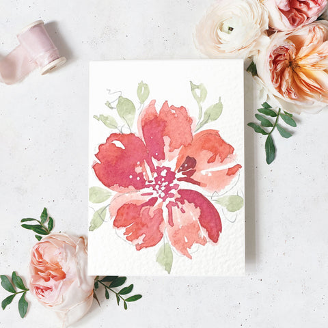 Floral card with watercolor design on a textured surface with flowers and ribbon.