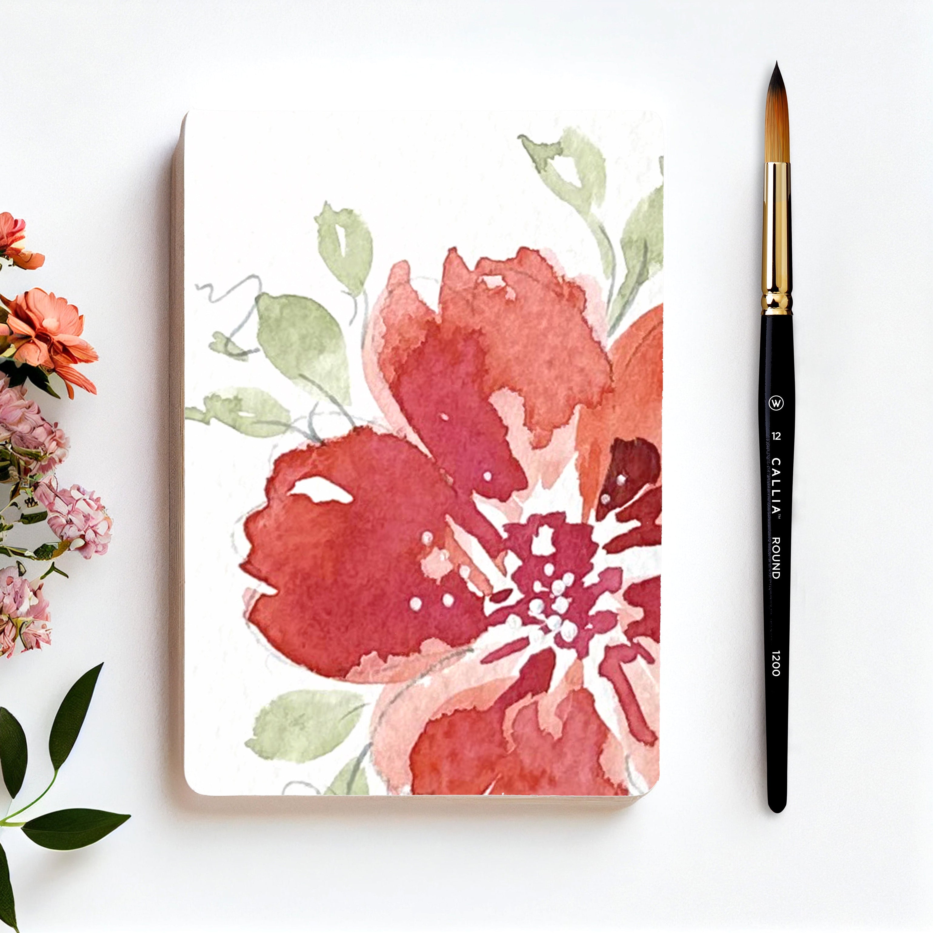 Floral notebook with flowers and a brush on a white background