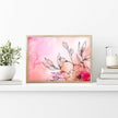 Framed floral artwork with pink watercolor background on a white shelf.